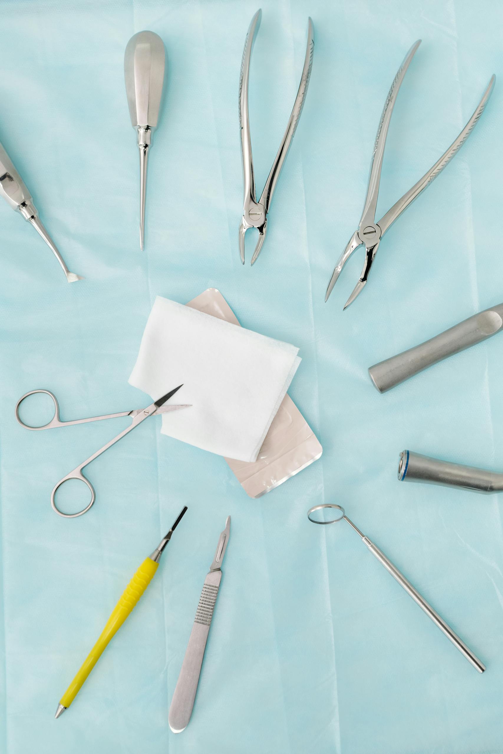 Top view of assorted dental surgical instruments on a blue background, sterile and ready for use.