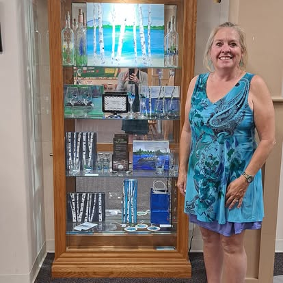 Artist in front of the display case with her work