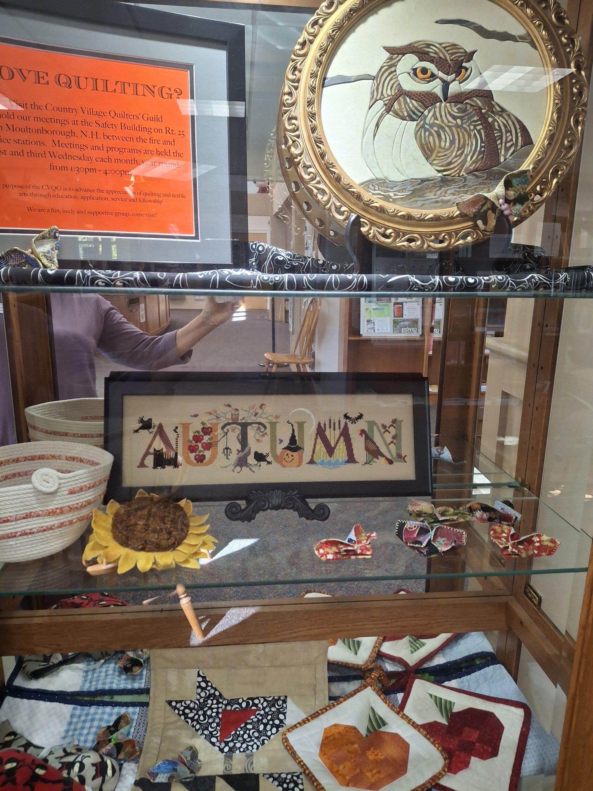 Display case filled with quilted work and embroidery.